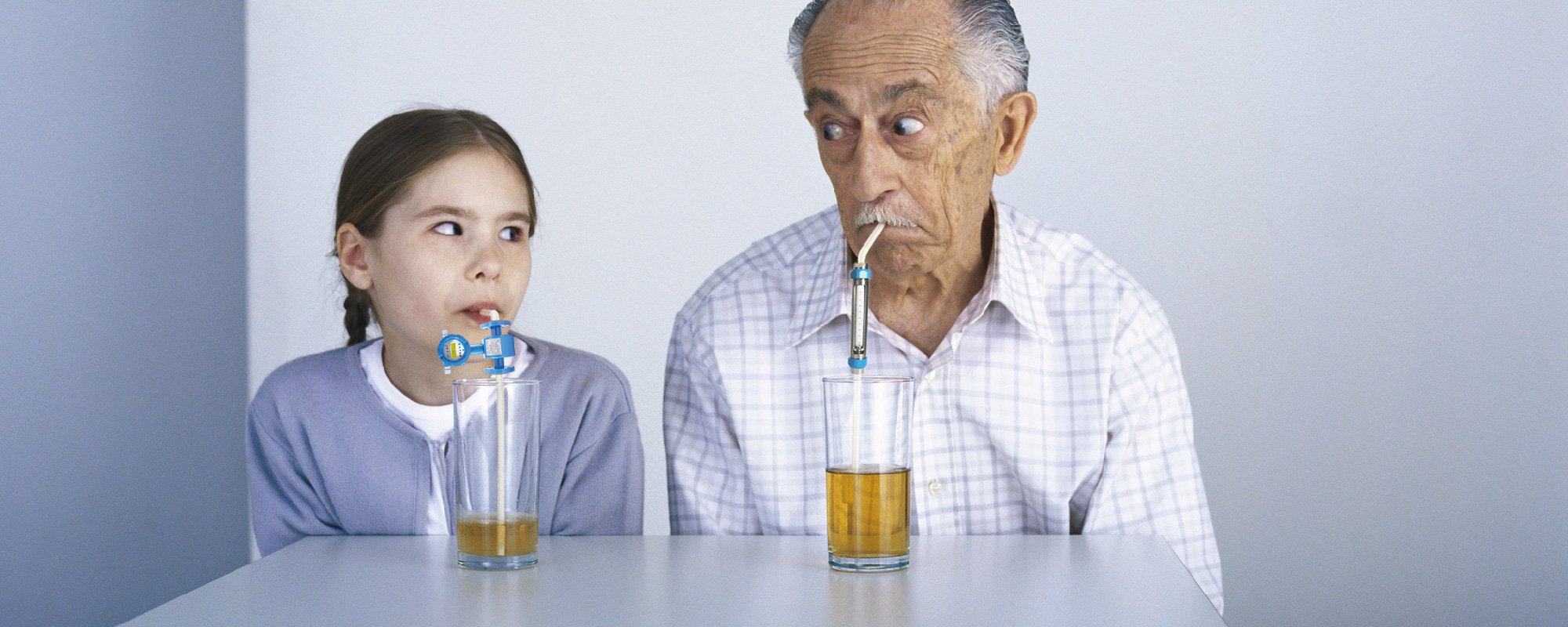 Junge Frau und älterer Mann trinken aus Glas mit einem Trinkhalm___